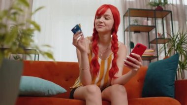 Plastik kredi kartı reklamları yapan, nakitsiz alışveriş yapan, indirimli internet sipariş alımı yapan kızıl saçlı genç bir kadın. Kızıl kız elinde akıllı telefon tutuyor.