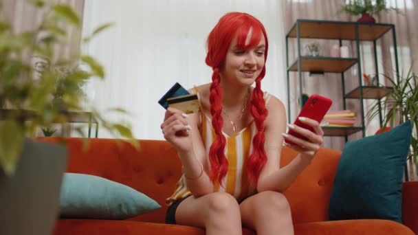 Kanepede Oturan Gülümseyen Kızıl Saçlı Kadın Kredi Kartı Akıllı Telefon — Stok video