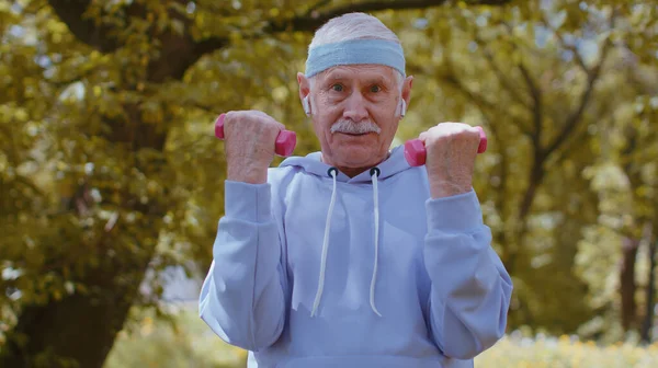 高齢者のフィットネス 強い高齢者の男性は 公園でスポーツトレーニングを練習し ダンベルウェイトリフティング演習を作る運動 現役引退した高齢者 健康的なライフスタイルを楽しむ祖父 — ストック写真