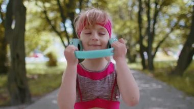 Spor sporu koşucusu kız eğitiminin portresi, kulaklıkla favori müzik şarkısı dinlemek. Sabah parkında egzersiz. Yürüyen çocuk koşucusu sağlıklı yaşam tarzını seviyor. Etkin çocuklar