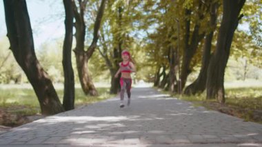 Atletik fitness sporu koşucusu kız çocuk yarışı bitiriyor, zafer. Kutlama, dans. Parkta kardiyo antrenmanı. Yürüyen çocuk koşu şampiyonu maratonu kazanıyor. Çocuk motivasyonu