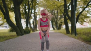 Koşu antrenmanından sonra ara veren yorgun spor koşucusu kız çocuğu. Parkta kardiyo çalışması. Yürüyen çocuk koşu maratonunu başarıyla tamamladı. Aktif çocuk motivasyonu