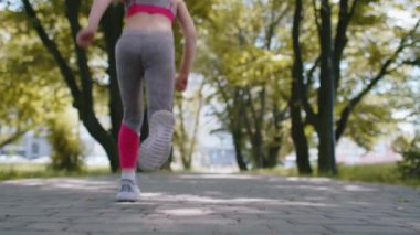 Sporcu formundaki koşucunun, yürümeye başlayan kızın maraton antrenmanının, kamera önünde koşuşunun arka görüntüsü. Parkta kardiyo çalışması. Çocuk sağlıklı yaşam tarzını seviyor. Etkin çocuklar
