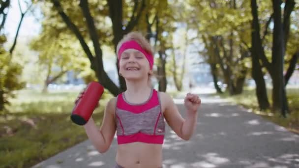アスレチックスポーツランナーの幼児の子供のジョギングは面白いダンスをお楽しみください 子供の女の子のトレーニングフィットネスエクササイズカメラに楽しいダンスBluetooth音楽スピーカーを聞いています 公園で心臓を働かせなさい アクティブな子供たち — ストック動画