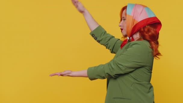 Gyönyörű vörös hajú nő mutatja hüvelykujját, rámutatva üres hely, reklám terület kereskedelmi szöveg, másolás helyet áruk promóció. Fiatal vörös lány. Stúdió lövés beltéri sárga fal háttér