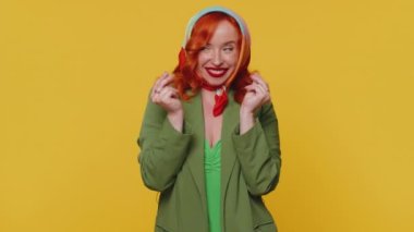 Eşarplı neşeli, zengin, kızıl saçlı kadın el hareketini boşa harcıyor ya da etrafa para saçıyor. Daha fazla bahşiş, büyük kar getiren vücut dilini hayal ediyor. Sarı stüdyo arka planında yalnız poz veren genç kız