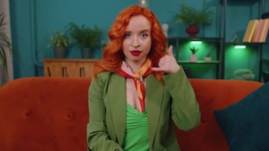 Ara beni, bu iletişim numarası. Kızıl saçlı genç bir kadın kameraya bakıyor ve telefon hareketleriyle beni evden aradığını söylüyor. Oturma odasında kanepede oturan kızıl kız.