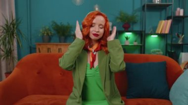 Sakin ol, rahatla, iç denge. Kadın derin nefes alıyor. Mudra jesti, gözleri kapalı. Yoğun düşüncelerle meditasyon yapıyor. Kızıl saçlı yetişkin kız oturma odasında kanepede oturuyor.