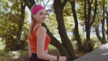 Atletik fitness sporunun arka görünüşü, koşucu kız motivasyonlu maraton koşusu, başparmak gösterme yarışına başlamak. Parkta kardiyo çalışması. Genç bir kadın koşmaktan hoşlanıyor. Aktif sporcu kadın koşucu