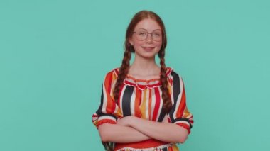 Gülümseyen mutlu kızıl saçlı kız göz kırpıyor, kameraya dişlek gülüşüyle bakıyor, göz kırpıyor ve flört ediyor, iyimserliğini ifade ediyor. Genç bir kızıl çocuk mavi stüdyoda izole edilmiş.