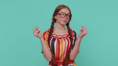 Parasını çarçur ettiğini ya da el hareketleriyle etrafa saçtığını gösteren neşeli, zengin, kızıl saçlı kız, daha fazla bahşiş, büyük kar getiren vücut dili hayal ediyor. Genç bir çocuk mavi stüdyo arka planında izole edilmiş.