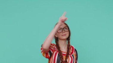 Güzel, kızıl saçlı kız çocuğu boş bir yeri işaret ediyor. Reklam için reklam alanı, ürün tanıtımı için fotokopi alanı. Mavi stüdyo geçmişinde genç kızıl bir çocuk.