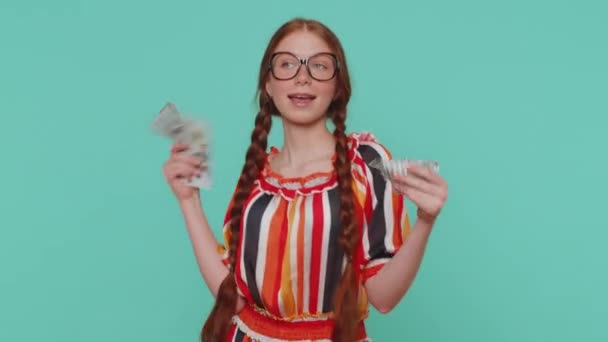 红头发的年轻女孩拿着现金钞票庆祝舞会 成功的商业生涯 彩票游戏的获胜者 大收入 蓝色工作室背景下的红头发少年孤身一人 — 图库视频影像