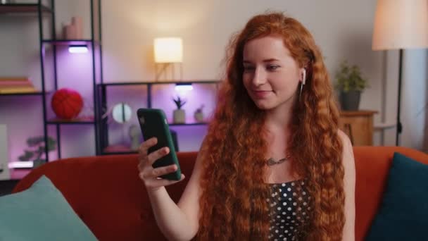 Una Joven Pelirroja Sonriente Usa Auriculares Haciendo Llamadas Conversación Con — Vídeos de Stock