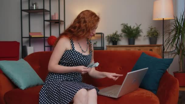规划预算 有钱的红头发女人数钱时 用笔记本电脑计算家里的账单 满足于收入的快乐女孩 为计划的假期 礼物存钱 — 图库视频影像