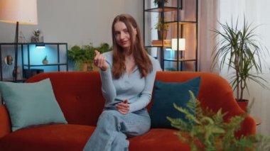 Neşeli, zengin, genç bir kadın el hareketini boşa harcıyor ya da etrafa para saçıyor. Daha fazla bahşiş, büyük kâr, piyango, vücut dili, paylaşım. Evdeki güzel kız kanepede oturuyor.