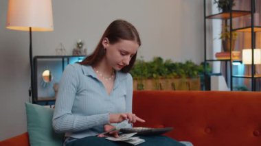 Planlama bütçesi. Zengin, mutlu, genç bir kadın nakit sayıyor hesap makinesi kullanıyor ve evdeki faturaları hesaplıyor. Gelir getiren, kazanan, planlı tatil için para biriktiren, hediyeler alan neşeli bir kız.