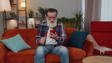 Heyecanlı yaşlı büyükbaba cep telefonu daktilo kullanıyor ve 