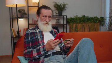 Alışverişkolik tüketici kıdemli büyükbaba evde oturmuş online yemek siparişi veriyor kredi kartı ile ödeme yapıyor. İnternette indirimli satış. Yaşlı emekli adam.