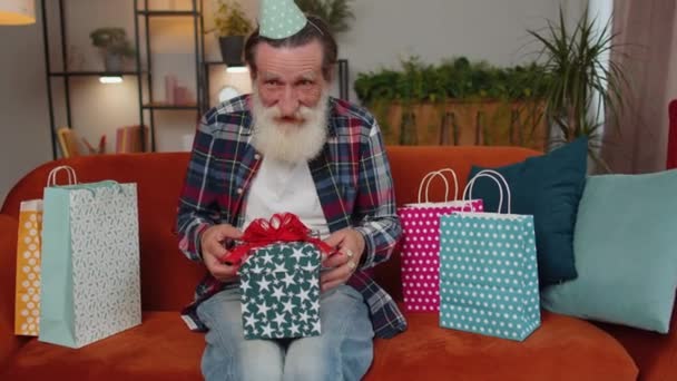 Šťastný Seniorský Děda Nosí Slavnostní Narozeninovou Čepici Dárkovou Krabičkou Blahopřáním — Stock video