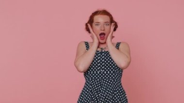 Aman Tanrım, vay canına. Heyecanlı kazanan kızıl saçlı kadın büyük gözleriyle kameraya bakarken şaşkınlıkla ellerini kaldırıyor, ani zaferden şok oluyor. Samimi bir genç kız pembe stüdyo arka planında yalnız başına.