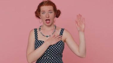 I swear to be honest. Sincere responsible redhead woman raising hand to take oath, promising to be honest and to tell truth keeping hand on chest. Ginger girl with freckles isolated on pink background