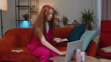 Planlama bütçesi. Zengin, mutlu, kızıl saçlı, nakit sayan bir kız. Laptop kullanıyor, ev faturalarını hesaplıyor. Neşeli çocuk gelir sağlar, planlı tatil için para biriktirir, hediyeler