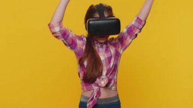 Young preteen child girl kid using virtual reality futuristic technology VR app headset helmet to play simulation 3D 360 video game, watching film movie. Little toddler children on yellow background