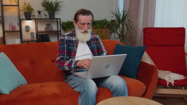 Überglücklicher Älterer Großvater Auf Der Heimischen Couch Mit Laptop Schrei — Stockvideo