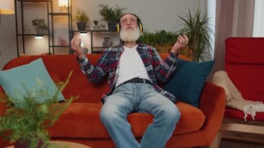 Sakin ol, rahatla, iç denge. Büyükbaba derin derin nefes alıyor Mudra jestleriyle gözleri kapalı meditasyon yaparak konsantre düşüncelerle, huzurlu bir zihinle evde kanepede oturuyor.