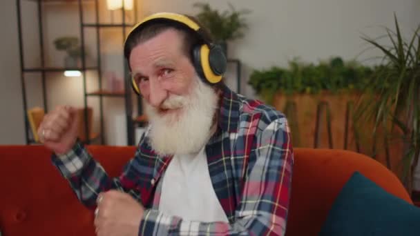 Happy Relaxed Overjoyed Grandfather Wireless Headphones Dancing Couch Home Choosing — 图库视频影像