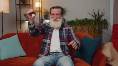 Yaşlı büyükbaba emlakçı el kaldırıyor yeni ev dairesinin anahtarlarını gösteriyor, ev satın alıyor ya da kiralıyor, ev kredisi veriyor. Odadaki adam kanepede oturuyor.