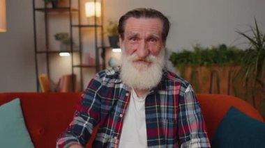 Yaşlı büyükbaba emlakçı el kaldırıyor yeni ev dairesinin anahtarlarını gösteriyor, ev satın alıyor ya da kiralıyor, ev kredisi veriyor. Odadaki adam kanepede oturuyor.