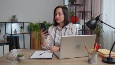 Young businesswoman working smartphone online remote distance job education sitting at table working from home office. Girl freelancer study, e-learning, texting share messages content on social media