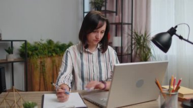 Genç bayan iş kadını belgeleri analiz ediyor sözleşme faturaları ya da grafik raporları okuyor ve ofis masasında laptopta çalışıyor. Kız serbest çalışma, internetten uzaktan öğrenme.
