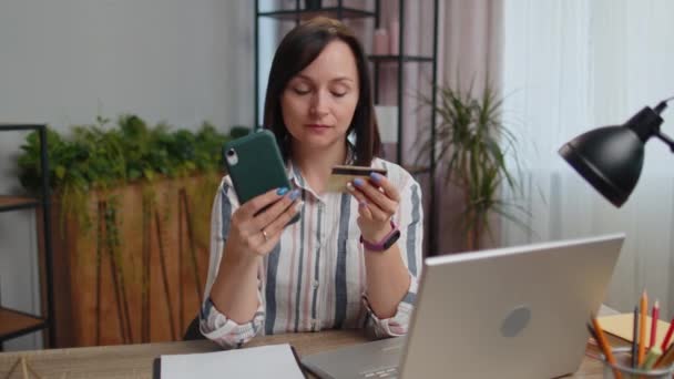年轻的女自由职业者在汇款时使用信用卡和智能手机 坐在总公司的办公桌旁购买网上购物 女生在网上远程工作学习 — 图库视频影像