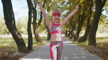 Sporcu spor koşucusu kız yarışmayı bitiriyor. Zafer ve başarı. Parkta kardiyo antrenmanı. Yürüyen çocuk koşu şampiyonu maratonu kazanıyor. Aktif çocuk motivasyonu