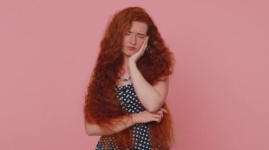 Diş sorunları. Genç kızıl saçlı kadın yanağa dokunuyor, gözleri korkunç bir ifadeyle kapanıyor diş ağrısı, hassas dişler, çürükler yüzünden acı çekiyor. Pembe arka planda çilli kızıl kız.