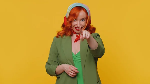 Hey you. Ginger woman in jacket smiling excitedly and pointing to camera, choosing lucky lottery winner, indicating to awesome you. Young redhead girl isolated alone on yellow studio wall background
