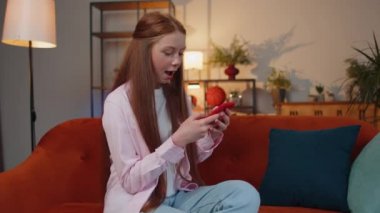 Mutlu, heyecanlı, neşeli, kızıl saçlı genç kız cep telefonu daktilo yazarak 