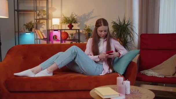 Young Teen Child Girl Lying Sofa Uses Mobile Phone Smile — Vídeo de Stock