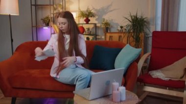 Ödenmemiş banka borçlarına bakan, kağıt işleri yapan, bütçe planlayan ev kredisi ödemelerini hesaplayan stresli, genç bir kız çocuğu. Kızıl saçlı çocuk kağıt para fırlatıyor.