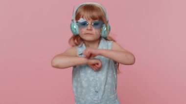 Kulaklıkla müzik dinleyen, dans eden disko yapan, kendini ifade eden eğlenceli elleri olan çocukluk çağındaki mutlu çocuk. Stüdyo pembe arka planda izole edilmiş küçük çocuklar.