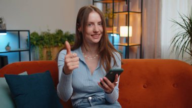 Genç bir kadın cep telefonuyla yazı yazarak 