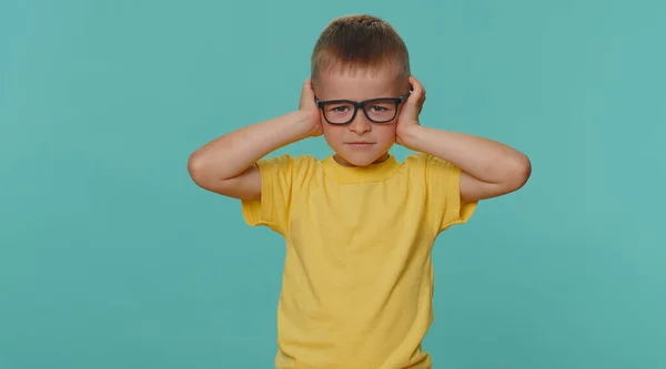Dont want to hear and listen. Frustrated annoyed irritated toddler children boy covering ears and gesturing No, avoiding advice ignoring unpleasant noise loud voices. Young kid on blue wall background