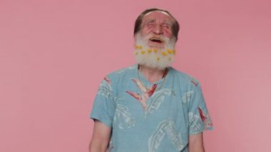 Joyful senior man laughing out loud after hearing ridiculous anecdote, funny joke, feeling carefree amused, positive people lifestyle. Elderly grandfather isolated alone on pink studio wall background