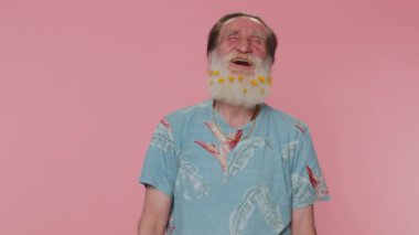 Joyful senior man laughing out loud after hearing ridiculous anecdote, funny joke, feeling carefree amused, positive people lifestyle. Elderly grandfather isolated alone on pink studio wall background