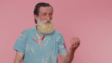 Yakışıklı, yaşlı bir adam boş bir yeri işaret ediyor ticari metinler için reklam alanı, ürün tanıtımı için fotokopi alanı. Yaşlı büyükbaba. Pembe arka planda kapalı stüdyo çekimleri
