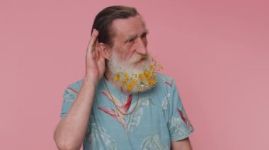 I cant hear you. What. Man trying hear you, looking confused and frowning, keeping arm near ear for louder voice, asking to repeat, to hear information, deafness. Senior grandfather on pink background
