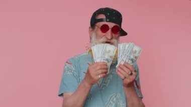 Zengin patron kıdemli patron, hayranı, başarılı bir iş adamı, piyango talihlisi, büyük gelir ve servet gibi banknotlar sallıyor. Yaşlı büyükbaba pembe stüdyo arka planında izole edilmiş.